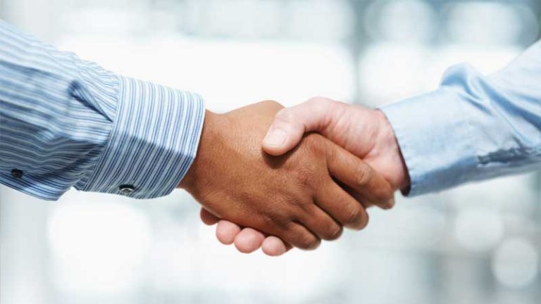 Stretta di mano tra due persone in camicia, simbolo di accordo e collaborazione professionale.